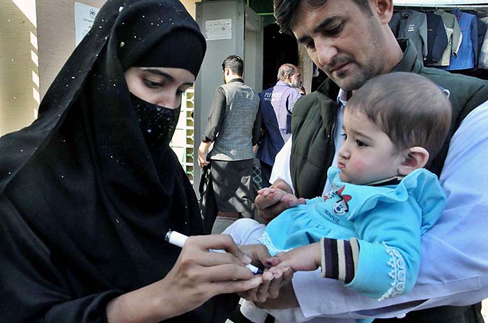 Health worker marking the finger of child after administering polio drops during anti polio campaign at Weekly Bazaar in Federal Capital.