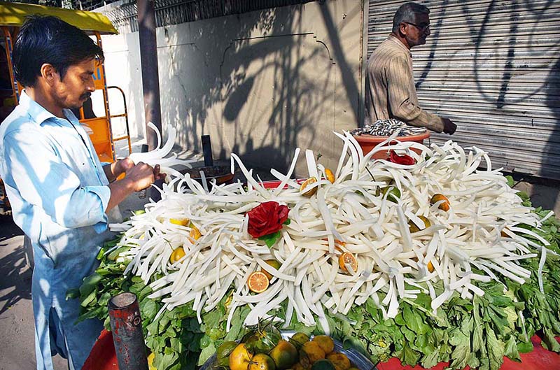 The vendor is cutting and displaying radishes to attract customers at his road side setup