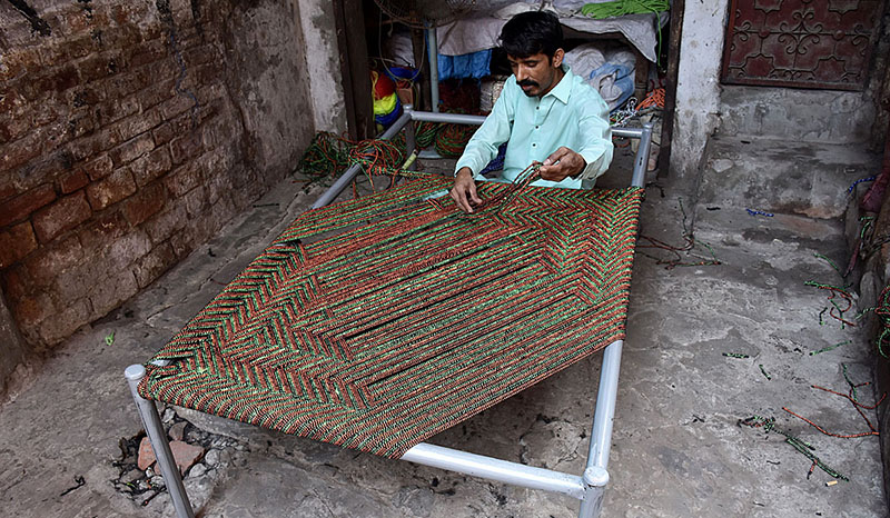 Worker busy in knitting traditional bed (charpai) at their workplace in the Provincial Capital.