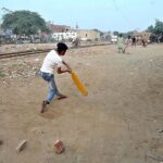 Children playing cricket along railway track at Old Civil Line