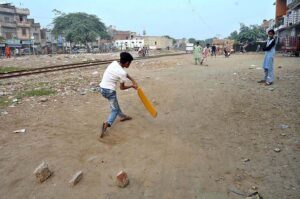 Children playing cricket along railway track at Old Civil Line