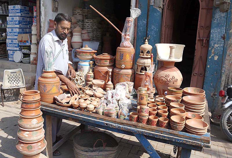 A vendor displacing clay-made items to attract the customers at Goods Naka Road
