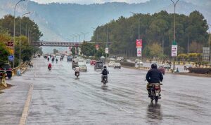 A motorcyclists on the way while cover with raincoat to protect from rain at Islamabad Expressway during light showers that experienced the Federal Capital.