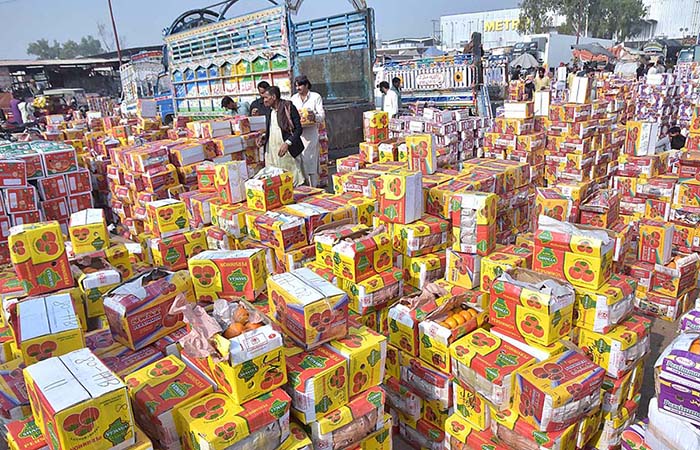 Vendors busy bidding of persimmon fruit boxes on whole sale rate at fruit and vegetable Market in the Federal Capital.