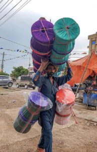 A street vendor in Khanna carrying straw-made stools and looking for customers. 