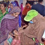 Lady Health Worker administering polio drops to a child during the 710th urs celebrations of Hazrat Shah Ruknuddin Alam Suhrawardi.