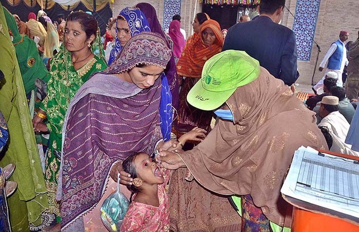 Lady Health Worker administering polio drops to a child during the 710th urs celebrations of Hazrat Shah Ruknuddin Alam Suhrawardi.