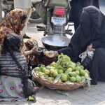 A woman purchasing guavas from roadside woman vendor