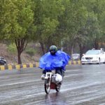 A motorcyclists on the way while cover with raincoat to protect from rain at Islamabad Expressway during light showers that experienced the Federal Capital.