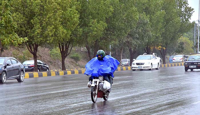 A motorcyclists on the way while cover with raincoat to protect from rain at Islamabad Expressway during light showers that experienced the Federal Capital.