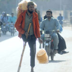 A disabled person selling edible stuff while shuttling on Khanewal Road.
