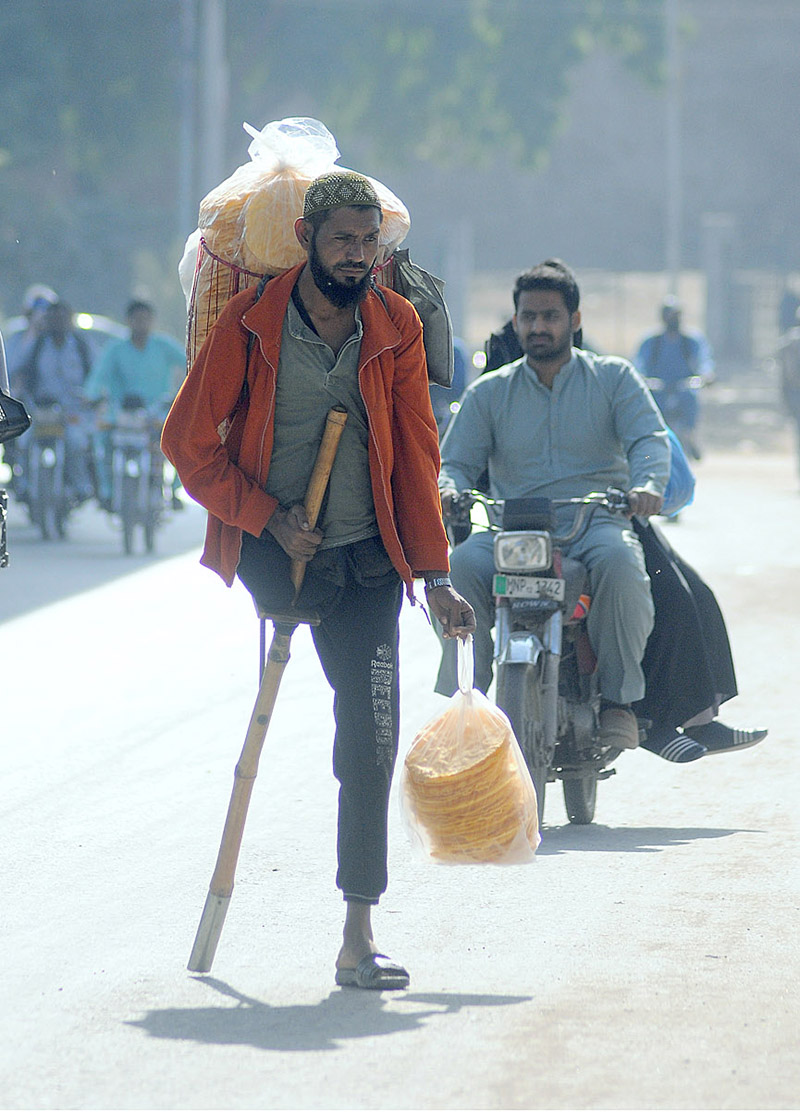 A disabled person selling edible stuff while shuttling on Khanewal Road.