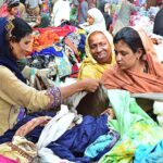 Women busy in selecting and purchasing old cloth pieces from vendor at cloth market road