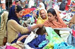 Women busy in selecting and purchasing old cloth pieces from vendor at cloth market road