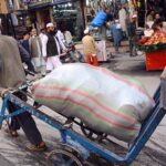 An old man carrying domestic items on his handcart at Qissa Khawani Bazar.