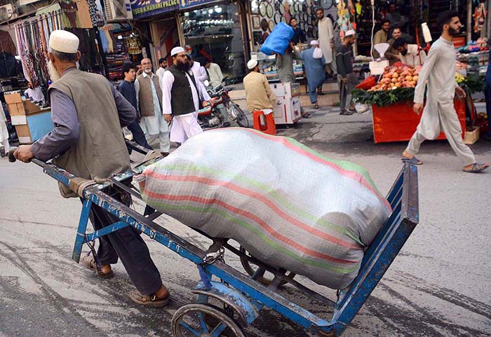 An old man carrying domestic items on his handcart at Qissa Khawani Bazar.