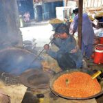 A worker busy in roasting food item (chana) at his workplace.