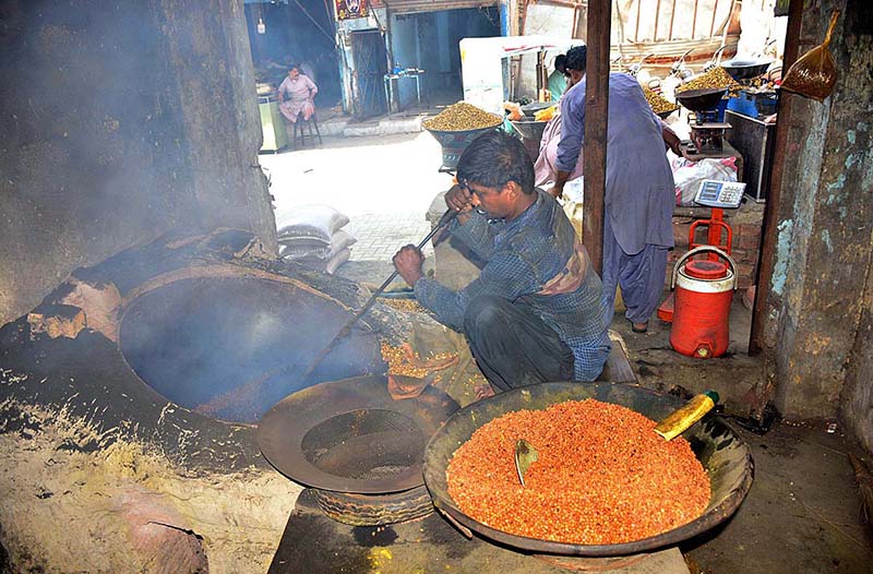 A worker busy in roasting food item (chana) at his workplace.