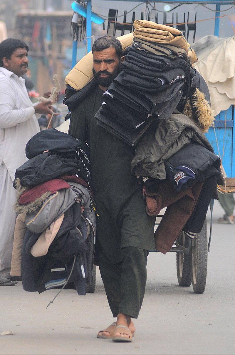 A street vendor displaying and selling jackets while shuttling on Hussain Agahi Road