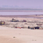 Laborers are loading sand onto tractor trolleys from the Chenab River.