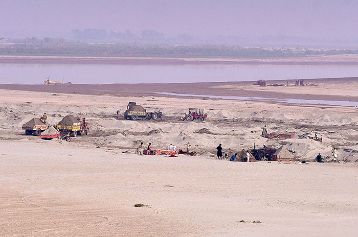Laborers are loading sand onto tractor trolleys from the Chenab River.