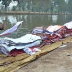 Laborer busy washing empty plastic bags in the canal