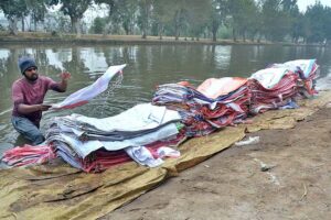 Laborer busy washing empty plastic bags in the canal