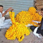 Vendors preparing garlands of fresh flowers to attract the customers at his shop.