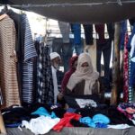 A woman selecting to purchase used clothes from a set-up by vendor in Saddar area