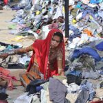 A woman labourer sorting old clothes at site area.
