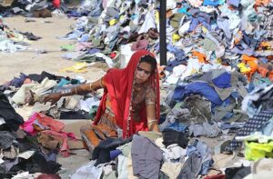 A woman labourer sorting old clothes at site area.