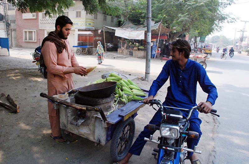 A vendor selling corncob to earn his livelihood on roadside in the city