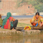 Gypsy women washing clothes while sitting on the edge of the Canal