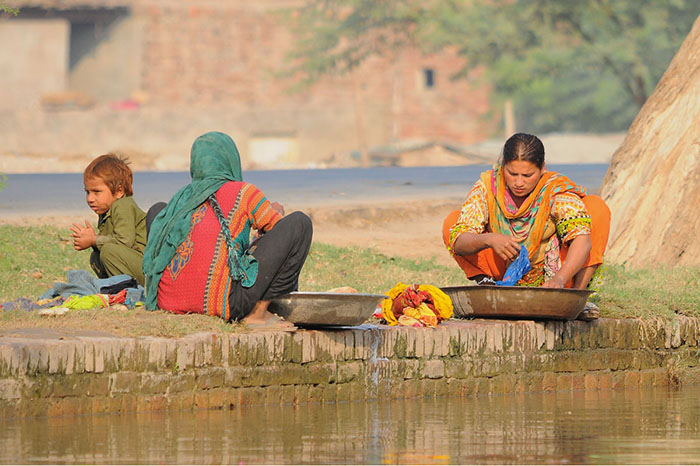 Gypsy women washing clothes while sitting on the edge of the Canal