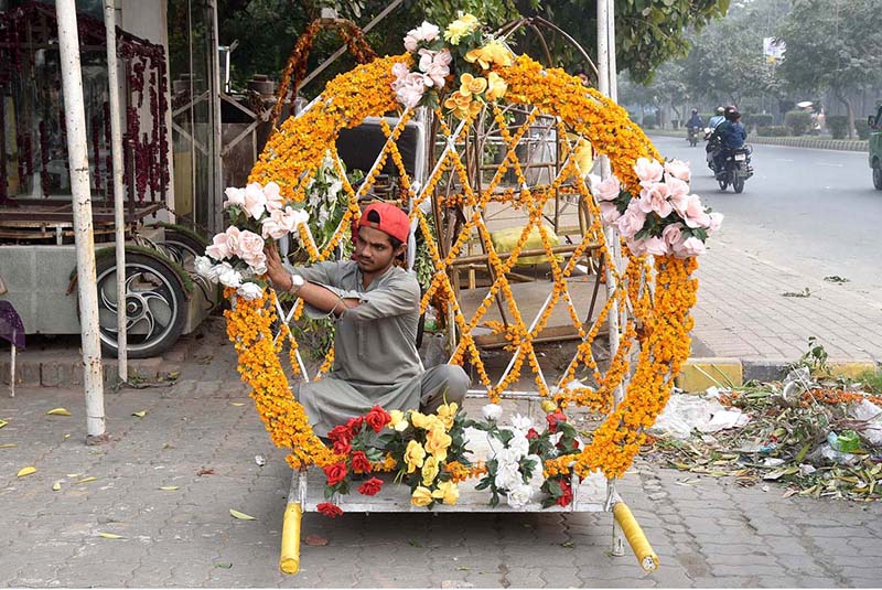 A vendor decorating his work place with flower garland used for a wedding and mehndi ceremony