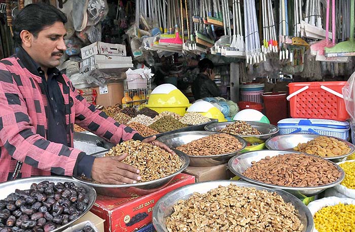 A shopkeeper arranging and displaying dry fruit to attract the customers at G-9 Markaz.