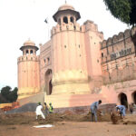 Labourers busy in restoration work on the wall of historical Shahi Qila