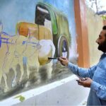 Artist busy in making wall paintings in front of the Press Club wall