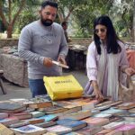 People are purchasing old books from the roadside vendor.