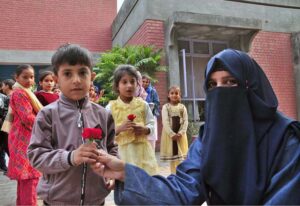 Students are presenting flowers to SOS Village children during an event organized by NCHD on the eve of World Children's Day at SOS Village
