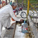 An elderly man filling his bottle with clean water from the filtration plant at Sitara Market