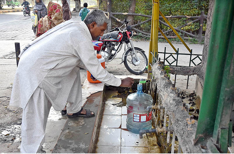 An elderly man filling his bottle with clean water from the filtration plant at Sitara Market