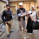 Polio worker administering polio drops to a child during anti-polio vaccination campaign in the Provincial Capital.