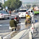 The NLC workers are inscribing text on the road at the square