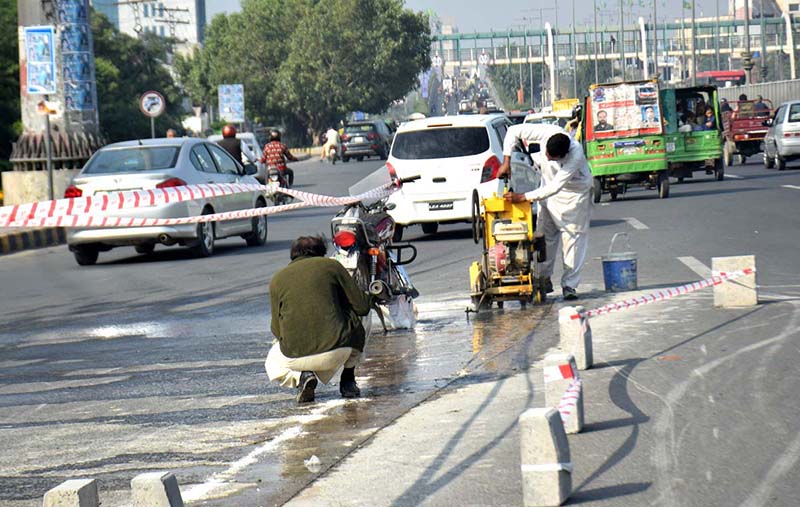 The NLC workers are inscribing text on the road at the square