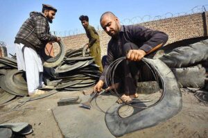 Laborers busy in cutting scrap tires at scrap tire godown