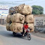 A young boy is loaded bags full of empty plastic bottles on a motorcycle which can cause any accident