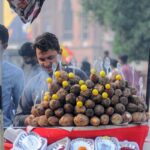 A vendor selling charcoal-roasted sweet potatoes to attract customers at his roadside setup