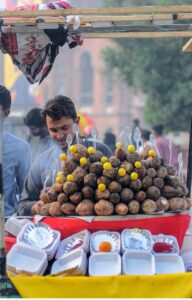 A vendor selling charcoal-roasted sweet potatoes to attract customers at his roadside setup