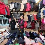 Vendor arranging and displaying old jackets and sweaters to attract the customers in the Hashtnagri area.